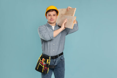 Professional builder with wooden planks on light blue backgroundの写真素材