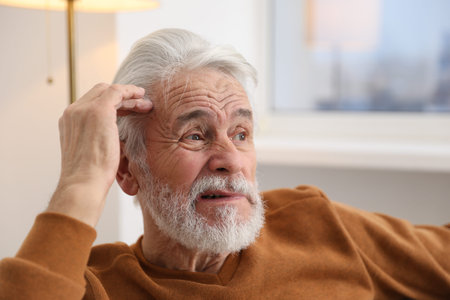 Amnesia. Senior man trying to remember something at home