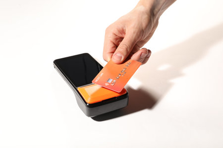 Man with credit card using payment terminal on white background, closeup