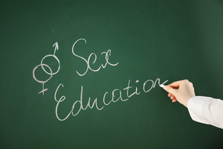 Woman writing words Sex Education on green chalkboard, closeupの写真素材
