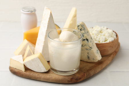 Different dairy products on white tiled table, closeup