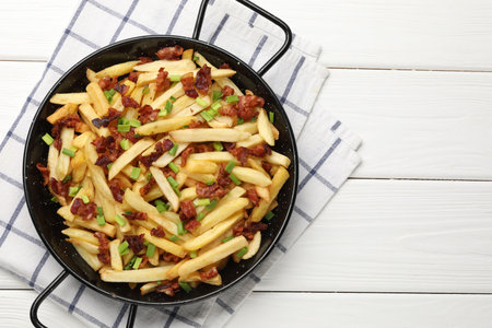 Delicious French fries with bacon and green onion on white wooden table, top view. Space for text