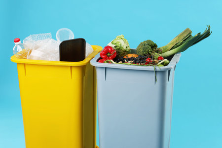Garbage in trash bins on light blue background, closeup. Waste sortingの写真素材