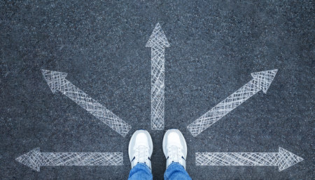 Man in sneakers standing on road with arrows pointing in different directions, top view. Start your...