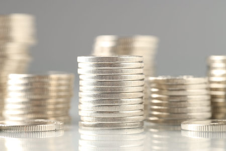 Many stacked coins on light background, closeup
