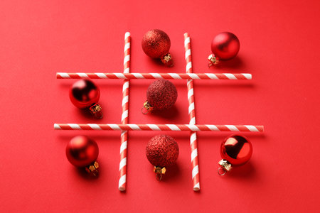 Tic tac toe game made with Christmas balls on red background
