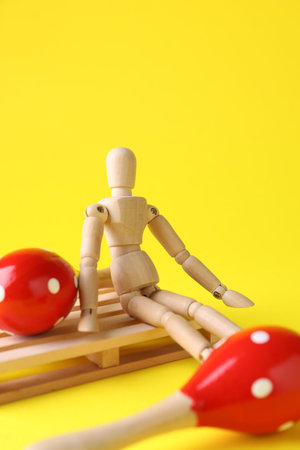 Wooden mannequin with toy maracas on yellow background, closeupの写真素材
