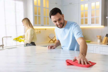 Couple tidying up kitchen together, selective focus. Domestic chores