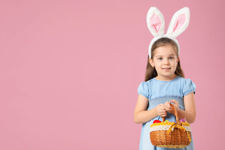 Easter celebration. Portrait of smiling little girl in headband with bunny ears holding wicker...