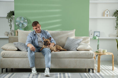 Young man with his cute dog relaxing on sofa at homeの写真素材