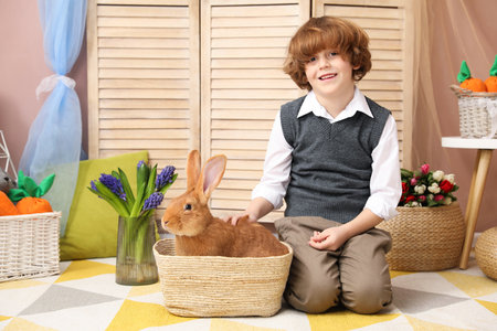 Little boy with cute Easter bunny in wicker basket indoorsの写真素材