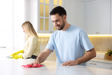 Couple tidying up kitchen together, selective focus. Domestic chores