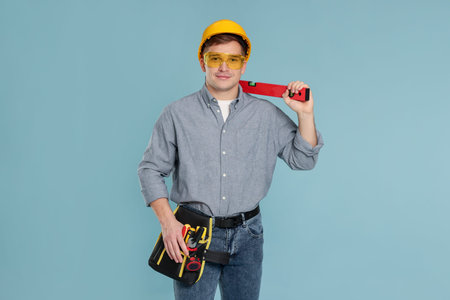 Professional builder with tools on light blue background