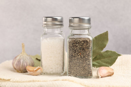 Salt and pepper shakers with spices on table, closeup