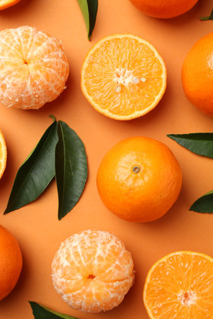 Fresh ripe tangerines and leaves on orange background, flat lay