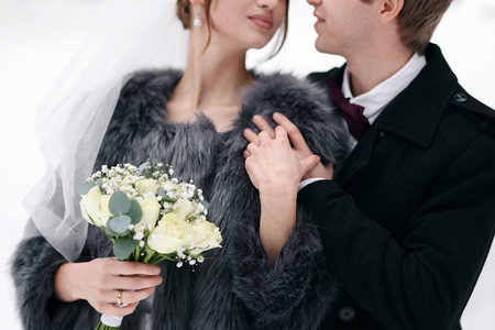 Newlywed couple with bouquet of flowers outdoors on winter day, closeupの写真素材