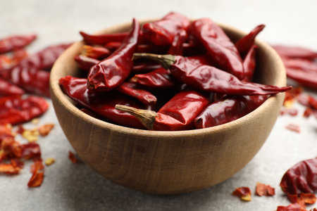 Red chili peppers in bowl on light grey table, closeup