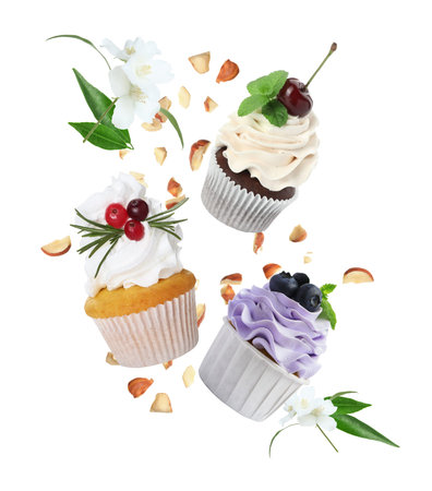 Delicious cupcakes with cream and berries flying in air on white backgroundの写真素材