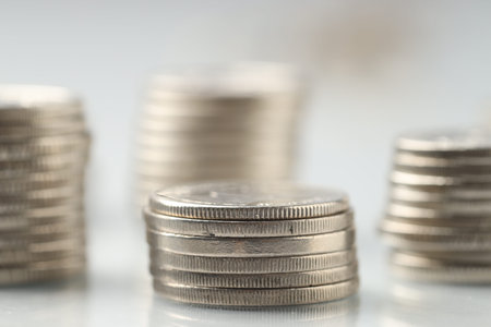 Many stacked coins on light background, closeup
