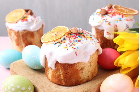 Delicious Easter cakes, tulips and painted eggs on table, closeup