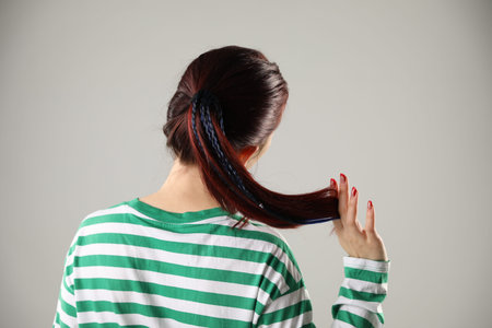 Woman with stylish braids on light grey background, back view