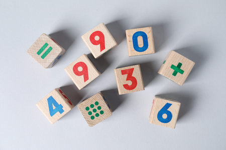 Wooden cubes with numbers and mathematical symbols on light background, flat lay