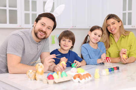 Easter celebration. Family painting eggs at white marble table in kitchenの写真素材