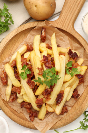 Delicious French fries with bacon served on white wooden table, flat lay