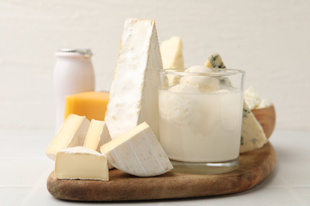 Different dairy products on white tiled table, closeup