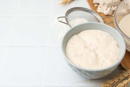 Yeast dough and ingredients on white tiled table, closeup. Space for text