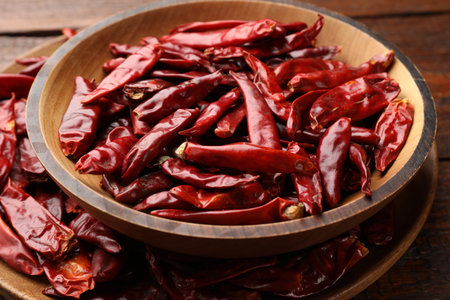Hot dried chili peppers on wooden table, closeup