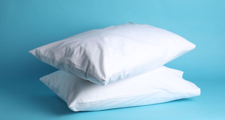 Bed linens. Pillows in clean pillowcases on light blue background
