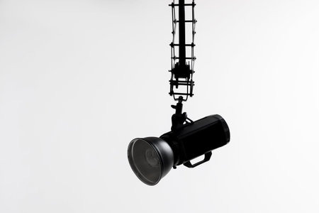 Professional lighting equipment hanging from ceiling in photo studio, space for text