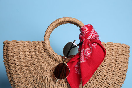 Stylish handkerchief, sunglasses and bag on light blue background, closeupの写真素材