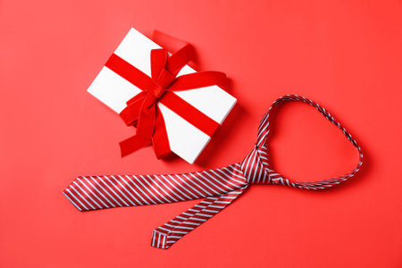 Stylish tie and gift box on red background, flat layの写真素材