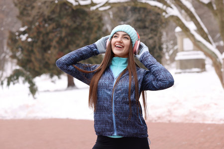 Portrait of woman with headphones in winter parkの写真素材