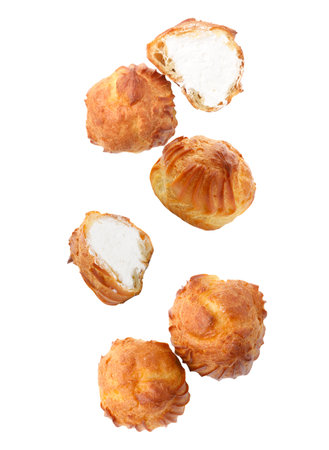 Yummy profiteroles with cream flying on white backgroundの写真素材