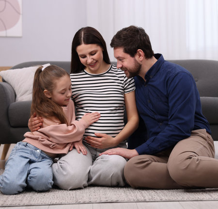 Pregnant woman, her husband and daughter on floor at homeの写真素材