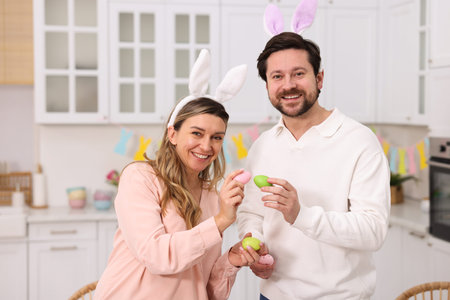 Easter celebration. Happy couple with painted eggs in kitchen