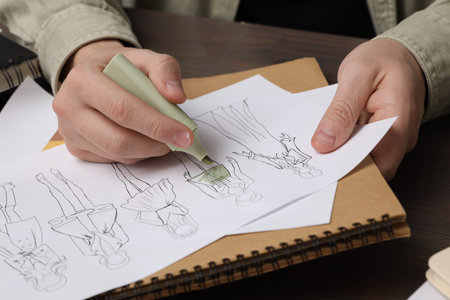 Fashion designer drawing sketch of outfits at wooden desk, closeupの写真素材