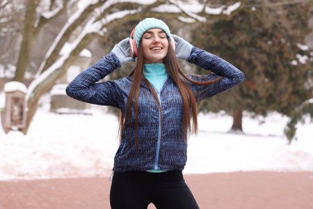 Portrait of woman with headphones in winter parkの写真素材