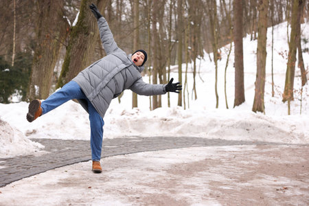 Young man falling on slippery pathway covered in ice outdoorsの写真素材