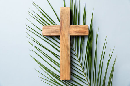 Easter attributes. Wooden cross and palm leaf on light gray background, top viewの写真素材