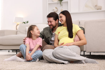Pregnant woman, her husband and daughter on floor at homeの写真素材