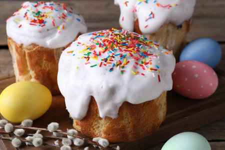 Delicious Easter cakes, painted eggs and willow branches on wooden table, closeup
