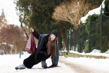 Young woman falling on slippery pathway covered in ice outdoors, space for textの写真素材
