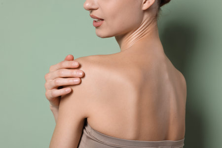 Young woman against green background, closeup. Body careの写真素材