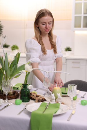 Woman setting festive table for Easter celebration at home