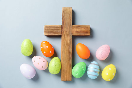 Wooden cross and painted Easter eggs on light gray background, flat layの写真素材