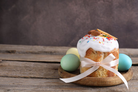 Delicious Easter cake and painted eggs on wooden table, closeup. Space for text